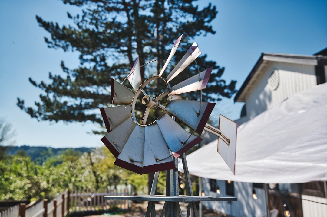 a-windmill-on-a-pole-in-front-of-a-house-q2fjt6e7ag